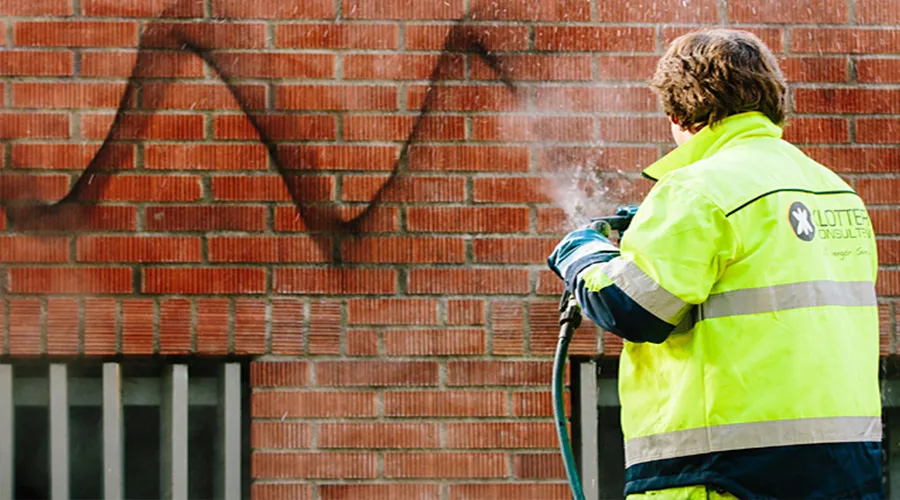 pågående klottersanering av tegelvägg